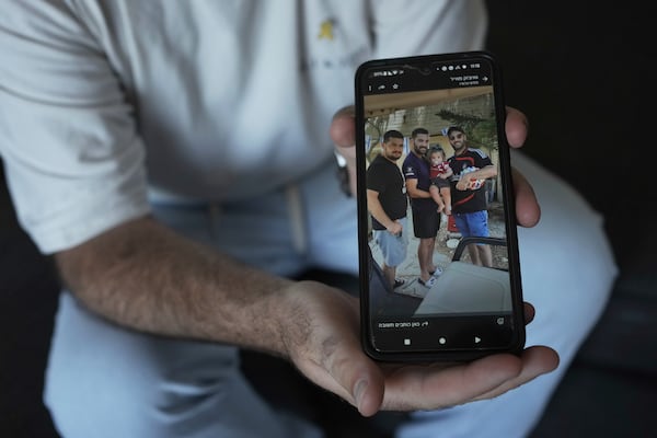 Liran Berman holds a picture on his mobile phone in Or Akiva, Israel, on Wednesday, June 25, 2025, showing himself, right, and brothers, Ziv, left, and Gali, center, who were abducted by Hamas-led militants on Oct. 7, 2023. (AP Photo/Maya Alleruzzo)