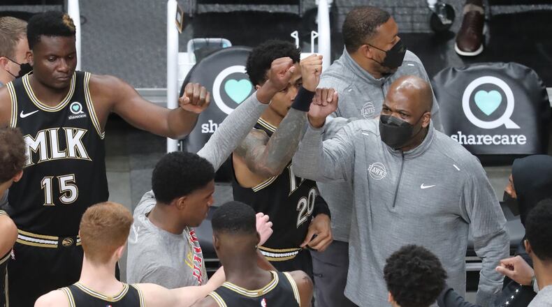 Hawks head coach Nate McMillan gives his players a fist bump as they take the court in March.  “Curtis Compton / Curtis.Compton@ajc.com”