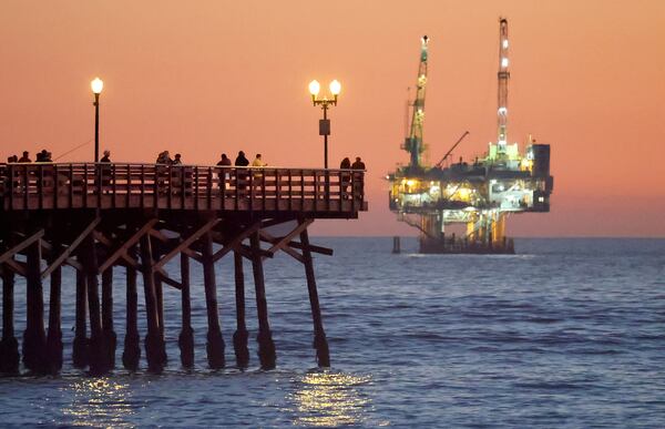 People stand on the the pier with offshore oil and gas platform Esther in the distance on Jan. 5, 2025, in Seal Beach, Calif. President Donald Trump is expected to open more areas to oil drilling, which has worried some on the Georgia coast. (Mario Tama/Getty Images/TNS)