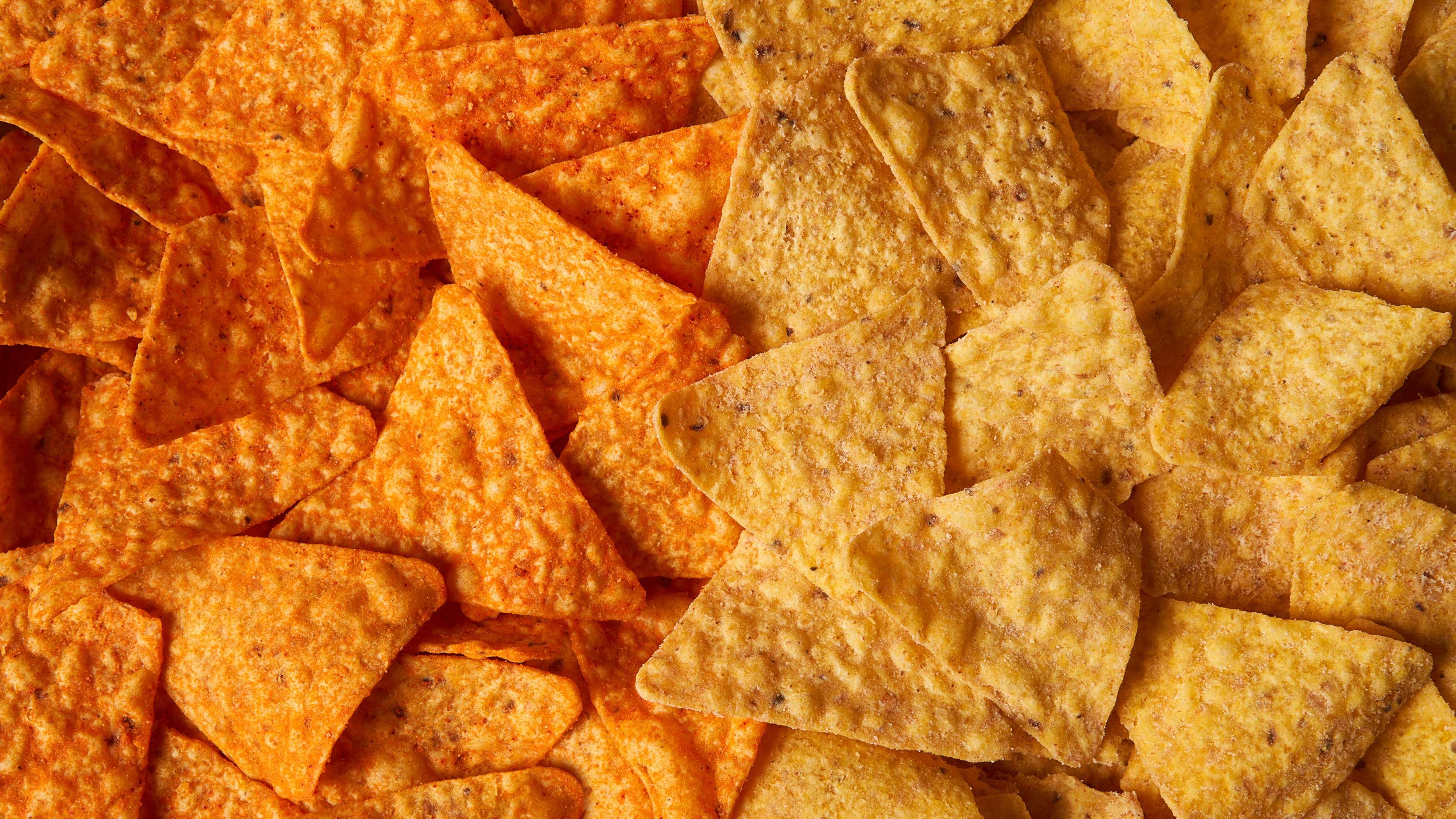 This image provided by PepsiCo shows from left, shows original Doritos Nacho cheese chips next to new Doritos without artificial colors or flavors. (PepsiCo via AP)