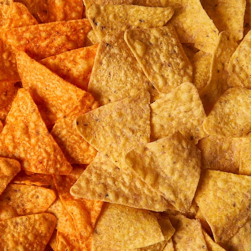 This image provided by PepsiCo shows from left, shows original Doritos Nacho cheese chips next to new Doritos without artificial colors or flavors. (PepsiCo via AP)