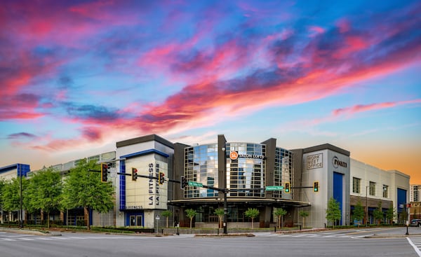 A corner shot of a commercial real estate development with a glass facade at sunset.