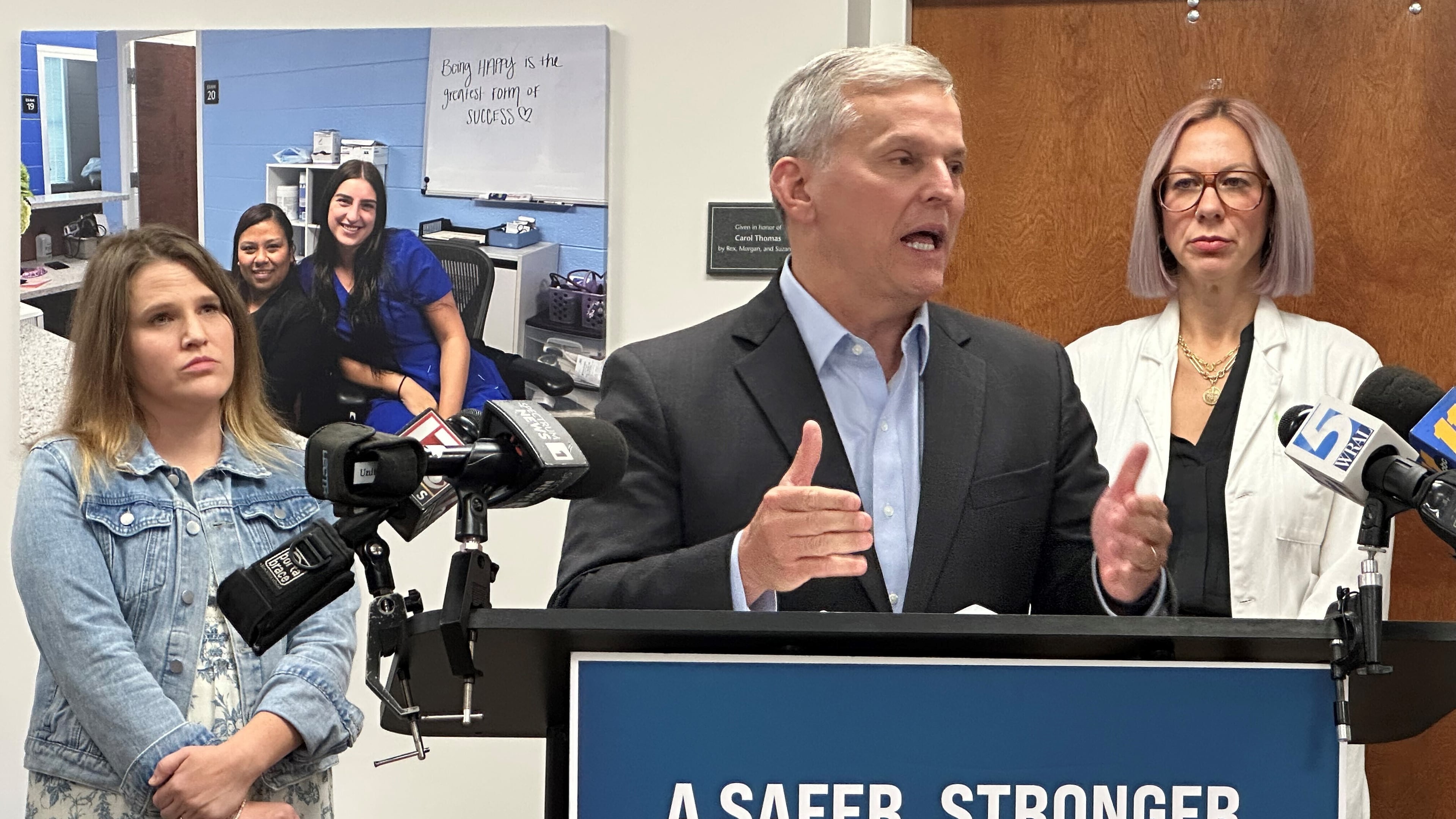 North Carolina Gov. Josh Stein speaks while Chelsea Gray of Rutherfordton, N.C., left, and Dr. Jenna Beckham, right, listen at a news conference about Medicaid reimbursement rate reductions at the Alliance Medical Ministry in Raleigh, N.C., on Thursday, Sept. 25, 2025 (AP Photo/Gary D. Robertson)