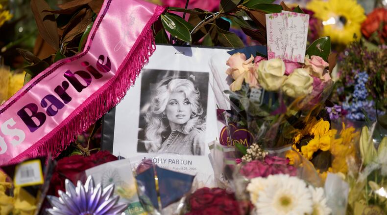 A portrait of the late Dolly Parton surrounded by flowers and cards in a memorial sits outside her home Thursday, Aug. 27, 2026, in Brentwood, Tenn. (AP Photo/George Walker IV)
