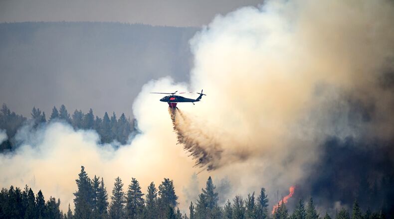 A helicopter drops water on the Akawa Butte fire on Friday, July 24, 2026, near Sisters, Ore. (AP Photo/Noah Berger)