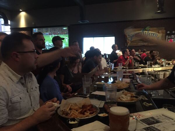 Fans cheer at the bar at Taco Mac in Dunwoody during the first quarter of the Falcons-Seahawks playoff game. ERIC STIRGUS/STAFF