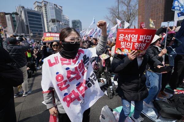 People react after hearing the news that President Yoon Suk Yeol was removed from office, in Seoul, South Korea, Friday, April 4, 2025. (AP Photo/Lee Jin-man)
