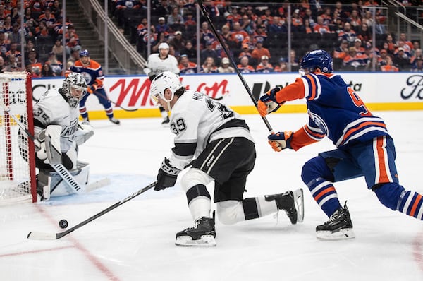 Los Angeles Kings' Jeff Malott (39) is chased by Edmonton Oilers' Jake Walman (96) as Kings' goalie Darcy Kuemper (35) follows the puck during the second period of an NHL hockey playoff game in Edmonton, Alberta, Friday, April 25, 2025. (Jason Franson/The Canadian Press via AP)