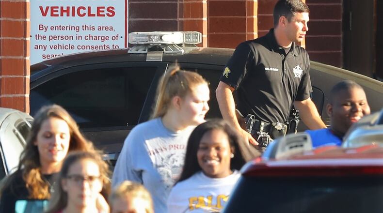 Students pass by a Laurens County Sheriff’s deputy stationed at East Laurens High School on Tuesday, May 2, 2018, in Dublin. Laurens County is the first school district in Georgia to allow teachers and other school personnel to carry weapons. An ad hoc school safety committee in Cherokee County, however, recently issued a report that opposes arming teachers and staff, other than certified police officers. Curtis Compton/ccompton@ajc.com (The Atlanta Journal-Constitution)