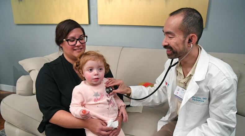 Lisa Maciel, of Hayward, holds her daughter Elyse, 2, as Heal.com pediatrician John Liou examines her on Friday, Jan. 19, 2018 at Maciel’s home in Hayward, Calif. Maciel hired Heal.com to find out if her daughter had a cold or the flu. Many people with the flu are heading to the ER and waiting for hours to see a doctor and running the risk of sitting next to others with even worse cases of the flu. Heal.com gives people another option by sending a primary care doctor to diagnose you at your home or office. (Doug Duran/Bay Area News Group/TNS)