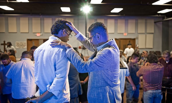 José Luis Orozco, a pastor from Nicaragua, places his hand on his son, Josias, 17, as he prays for him and the congregation of the Oasis Church, in Taylor, Texas, June 15, 2025. (AP Photo/Rodolfo Gonzalez)