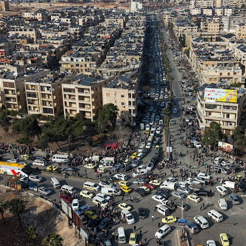 An aerial view shows Syrian residents in vehicles, queueing to flee from Sheikh Maqsoud and Achrafieh neighborhoods after clashes broke out on Tuesday between Syrian government forces and Kurdish fighters in a contested area of the northern city of Aleppo, Syria, Wednesday, Jan. 7, 2026. (AP Photo/Omar Albam)