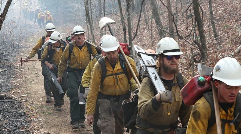 A California fire crew (right) walks toward the Rock Mountain fire last week while an Oregon crew (back) heads out after a long shift. CURTIS COMPTON / CCOMPTON@AJC.COM