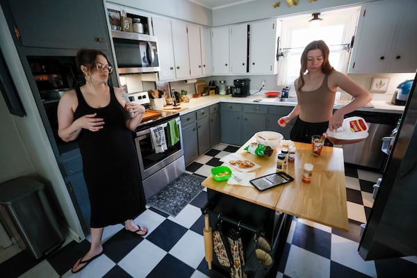 Emilia Pierce (right) pours a glass of store-bought sweet tea while talking with her mother, Stormy Bost, in the kitchen of their Calhoun home. The family no longer brews tea using local tap water. (Miguel Martinez/AJC) 
