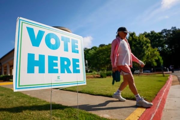 A person walks past a voting sign during the first day of early voting for the primary elections at the Dunwoody Library on Monday. (Miguel Martinez/AJC)