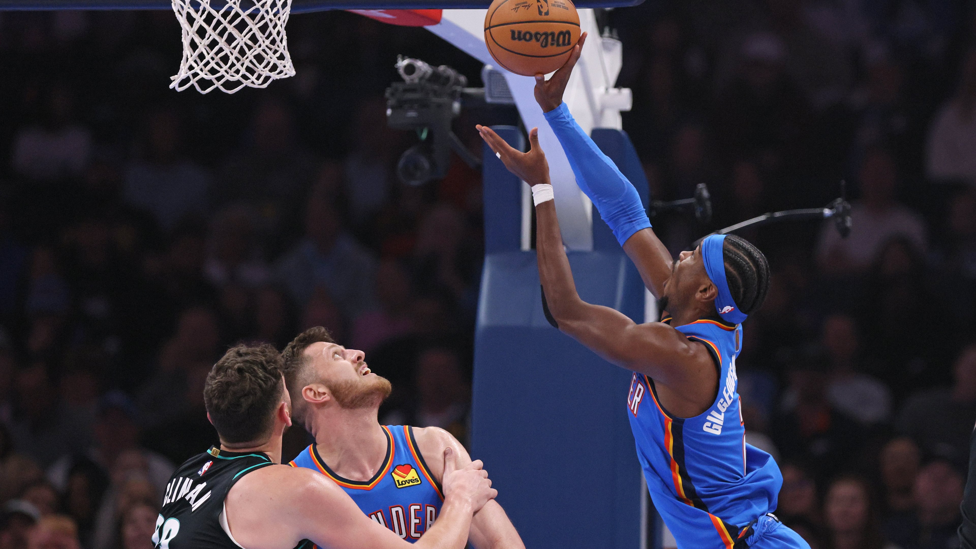 Oklahoma City Thunder guard Shai Gilgeous-Alexander, right, shoots next to Portland Trail Blazers center Donovan Clingan, left, and Thunder center Isaiah Hartenstein during the first half of an NBA basketball game, Sunday, Nov. 23, 2025, in Oklahoma City. (AP Photo/Nate Billings)