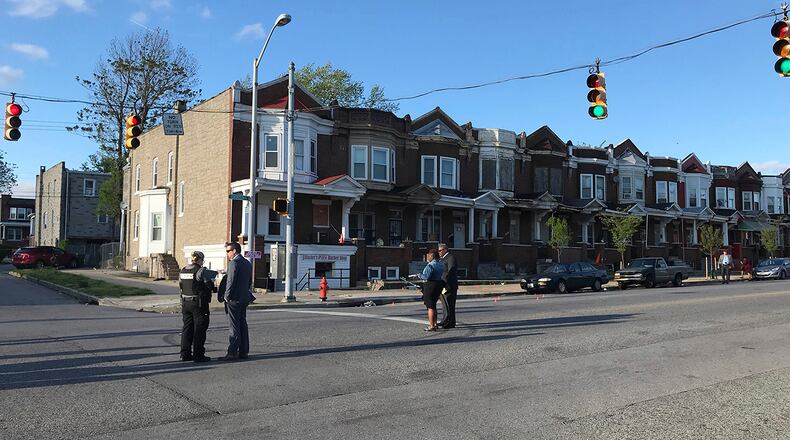 Authorities stand at Edmondson and Whitmore after multiple people were shot, Sunday, April 28, 2019, in west Baltimore. At least one person was killed and six others wounded.