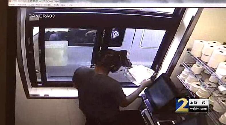 Surveillance footage appears to show a man pull up in a white Chevrolet and pass the cashier a note.