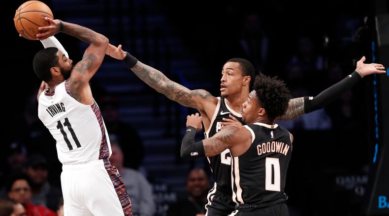 Brooklyn guard Kyrie Irving (11) passes as he is double teamed by Hawks forward John Collins (20) and guard Brandon Goodwin (0) during the first half Sunday, Jan. 12, 2020, in New York. It was Irving's first game in more than two months.