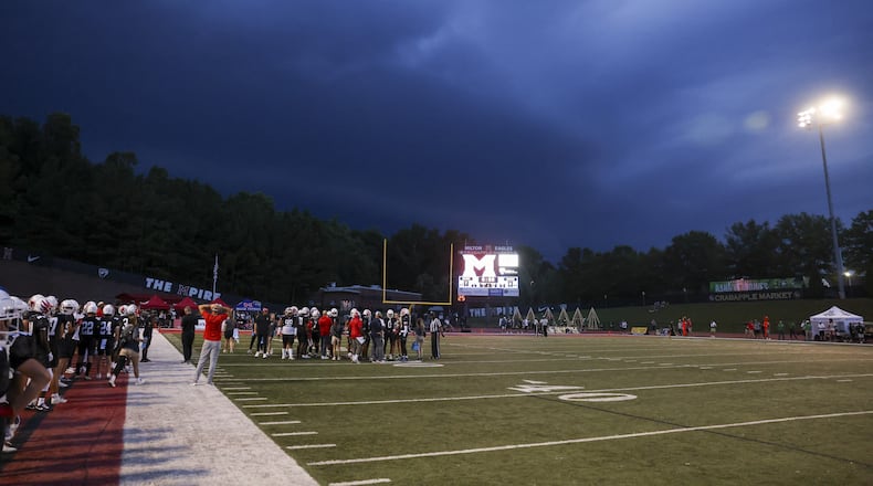 Storm clouds approach the stadium as the Milton defense huddles up against Buford in the first half at Milton High School, Friday, August 16, 2024, in Milton, Ga. (Jason Getz / AJC)