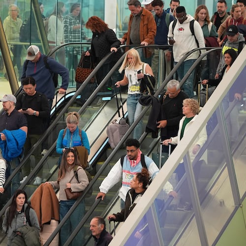 Travellers head tdown an escalator after clearing through a security checkpoint in Denver International Airport Friday, Nov. 7, 2025, in Denver. (AP Photo/David Zalubowski)
