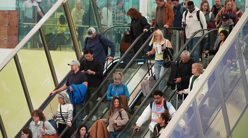 Travellers head tdown an escalator after clearing through a security checkpoint in Denver International Airport Friday, Nov. 7, 2025, in Denver. (AP Photo/David Zalubowski)