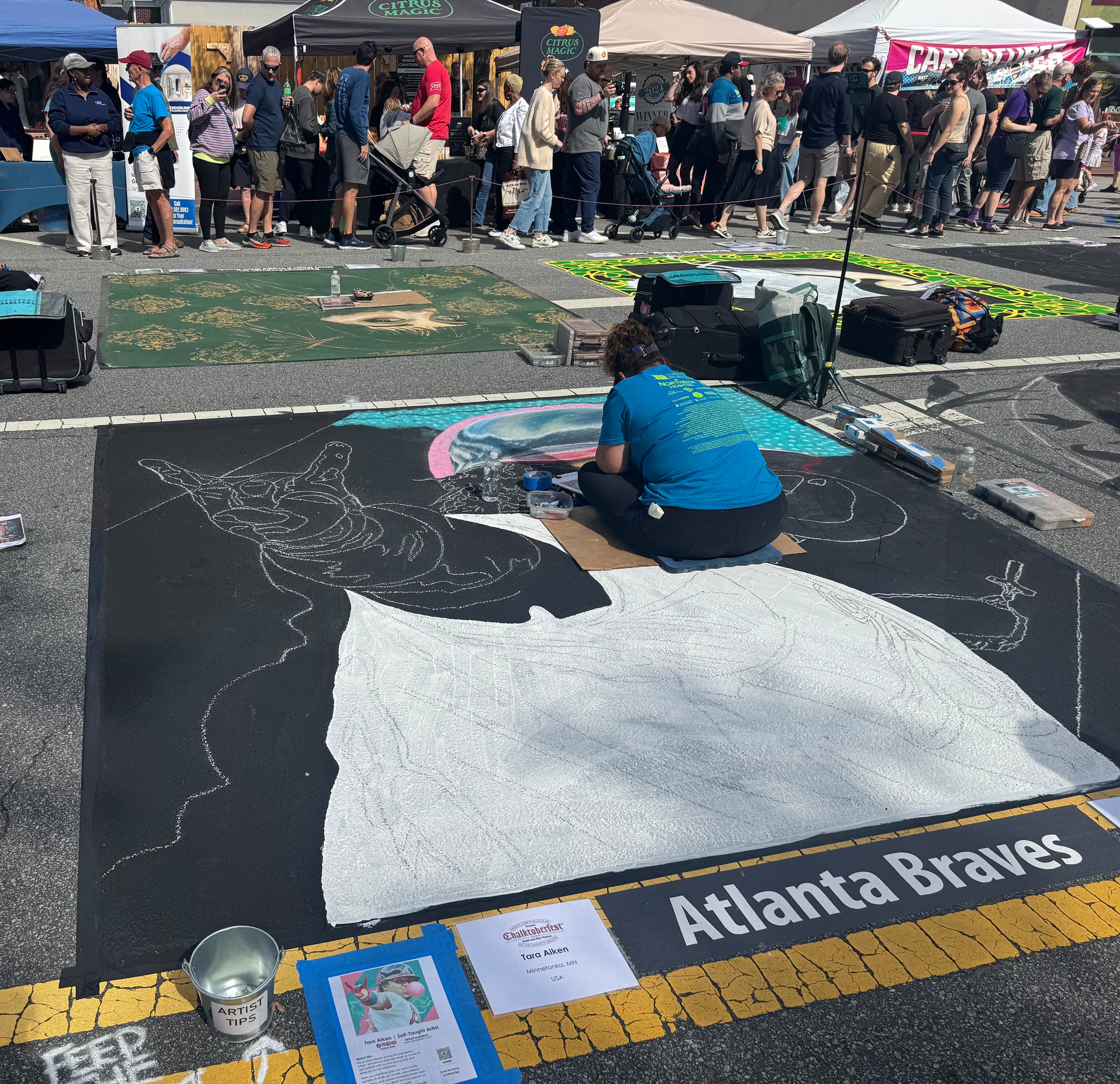 Tara Aiken, an artist based out of Minnetonka, Minn., works on a chalk drawing of Atlanta Braves star Ronald Acuña Jr. blowing a bubble at Chalktoberfest in Marietta on Saturday, Oct. 11, 2025. (Caleb Groves/AJC)