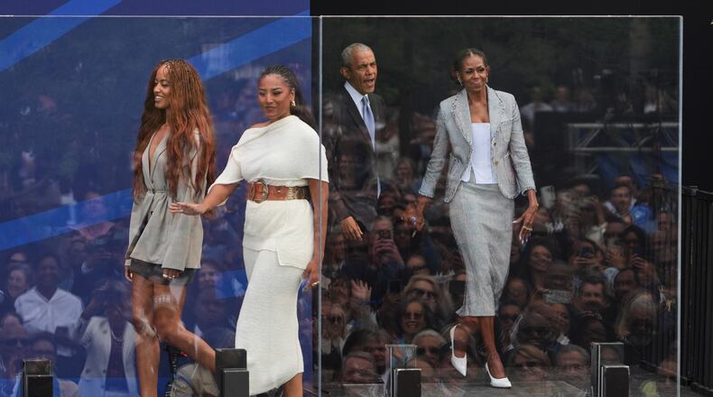 Former President Barack Obama, back center, and former first lady Michelle Obama, right, arrive on stage with their daughters, Sasha and Malia Obama, during the dedication ceremony for the Obama Presidential Center, Thursday, June 18, 2026, in Chicago. (AP Photo/Jeff Roberson)
