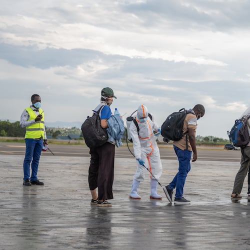 A health worker disinfects passengers prior to their boarding of the World Food Programme's (WFP) aircraft following the government's announcement of Bunia National Airport's reopening in Bunia, Congo, Tuesday, June 2, 2026. (AP Photo/Moses Sawasawa)