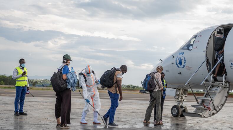 A health worker disinfects passengers prior to their boarding of the World Food Programme's (WFP) aircraft following the government's announcement of Bunia National Airport's reopening in Bunia, Congo, Tuesday, June 2, 2026. (AP Photo/Moses Sawasawa)