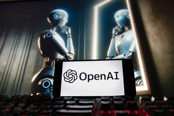 The OpenAI logo is displayed on a cellphone with an image on a computer monitor generated by ChatGPT's Dall-E text-to-image model in this 2023 photograph. (AP Photo/Michael Dwyer, File)