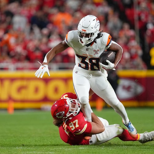 Denver Broncos running back Jaleel McLaughlin (38) rushes for a first down as Kansas City Chiefs defensive end Ashton Gillotte (97) tries to stop him during the first half of an NFL football game Thursday, Dec. 25, 2025, in Kansas City, Mo. (AP Photo/Ed Zurga)