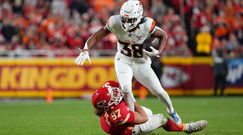 Denver Broncos running back Jaleel McLaughlin (38) rushes for a first down as Kansas City Chiefs defensive end Ashton Gillotte (97) tries to stop him during the first half of an NFL football game Thursday, Dec. 25, 2025, in Kansas City, Mo. (AP Photo/Ed Zurga)