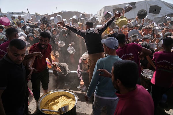 Palestinians struggle to get donated food at a community kitchen in Khan Younis, Gaza Strip, Friday, May 16, 2025. (AP Photo/Abdel Kareem Hana)