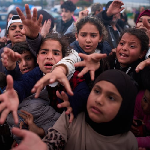 Displaced families extend their hands while waiting for donated food beside the tents they use as shelters after fleeing Israeli bombardment in southern Lebanon, in Beirut, Lebanon, Thursday, April 9, 2026. (AP Photo/Emilio Morenatti)