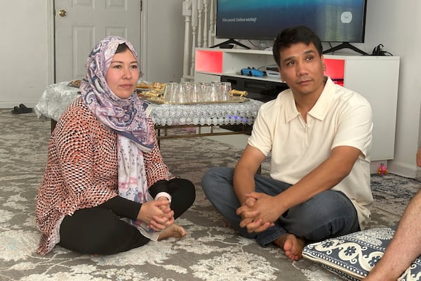 Nuriya Sharafoddin, left, and her husband, Mohammad Sharafoddin, right listen to a friend talking about the travel ban from Afghanistan to the U.S. at their home in Irmo, S.C., on Saturday, June 7 2025. (AP Photo/Jeffrey Collins)