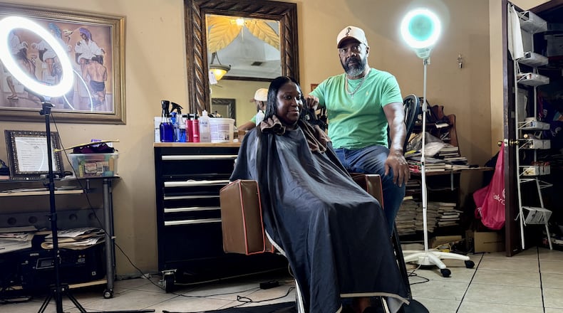 Hair stylist Garrett Milton, 66, tends to a client at his parlor in Fort Valley, the Hidden Image. Milton believes Kamala Harris will win November's presidential election. "You’re getting a Black female running for a Democratic presidency. … I think Black women are going to stand up and fight” for her, he said. (Joe Kovac Jr. / AJC)