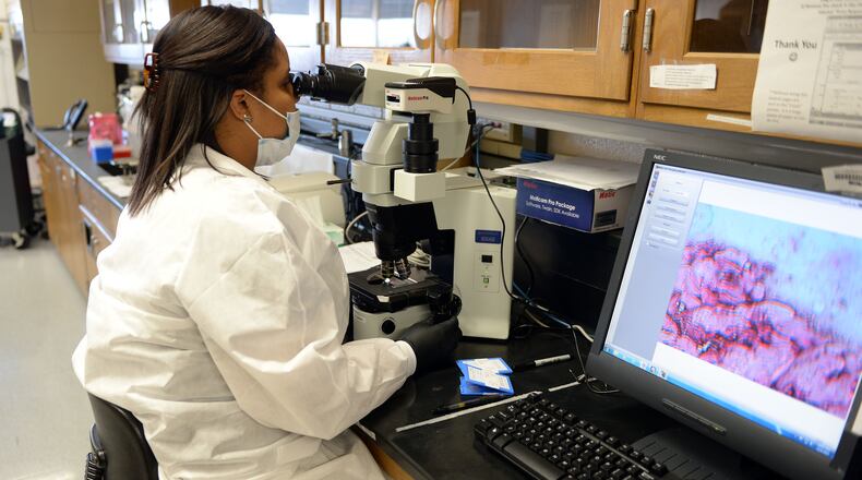 Scientist Lanisha Gittens uses a microscope as she works on evidence in the serology lab at the GBI crime laboratory in late 2015. KENT D. JOHNSON/ kdjohnson@ajc.com