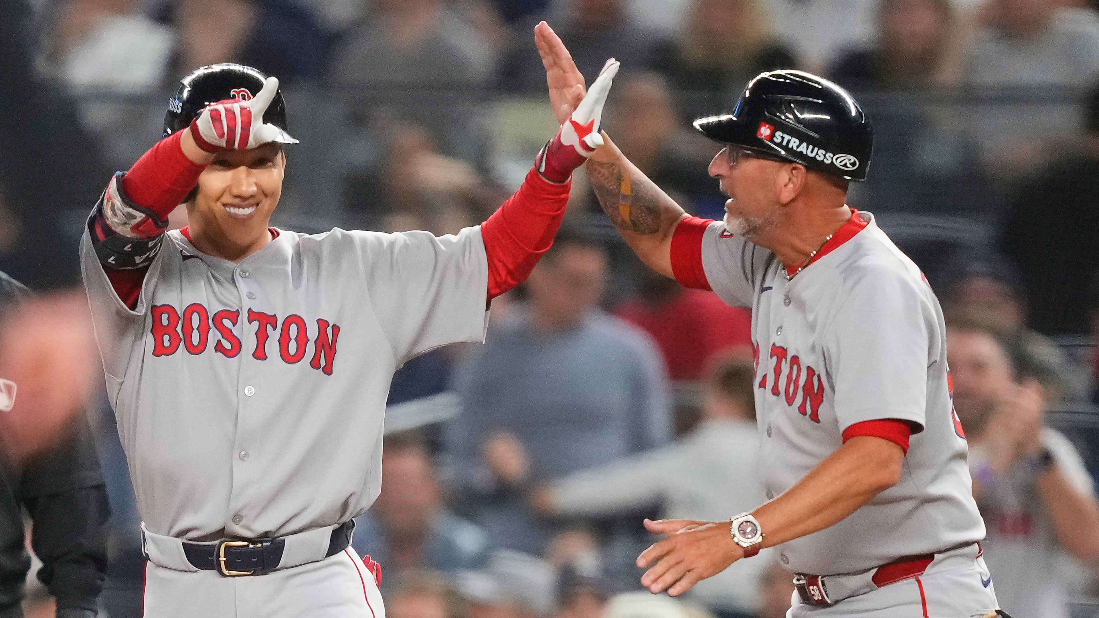 Boston Red Sox outfielder Masataka Yoshida, left, celebrates with first base coach José David Flores after driving in two runs against the New York Yankees during the seventh inning of Game 1 of an American League wild-card baseball playoff series, Tuesday, Sept. 30, 2025, in New York. (AP Photo/Yuki Iwamura)