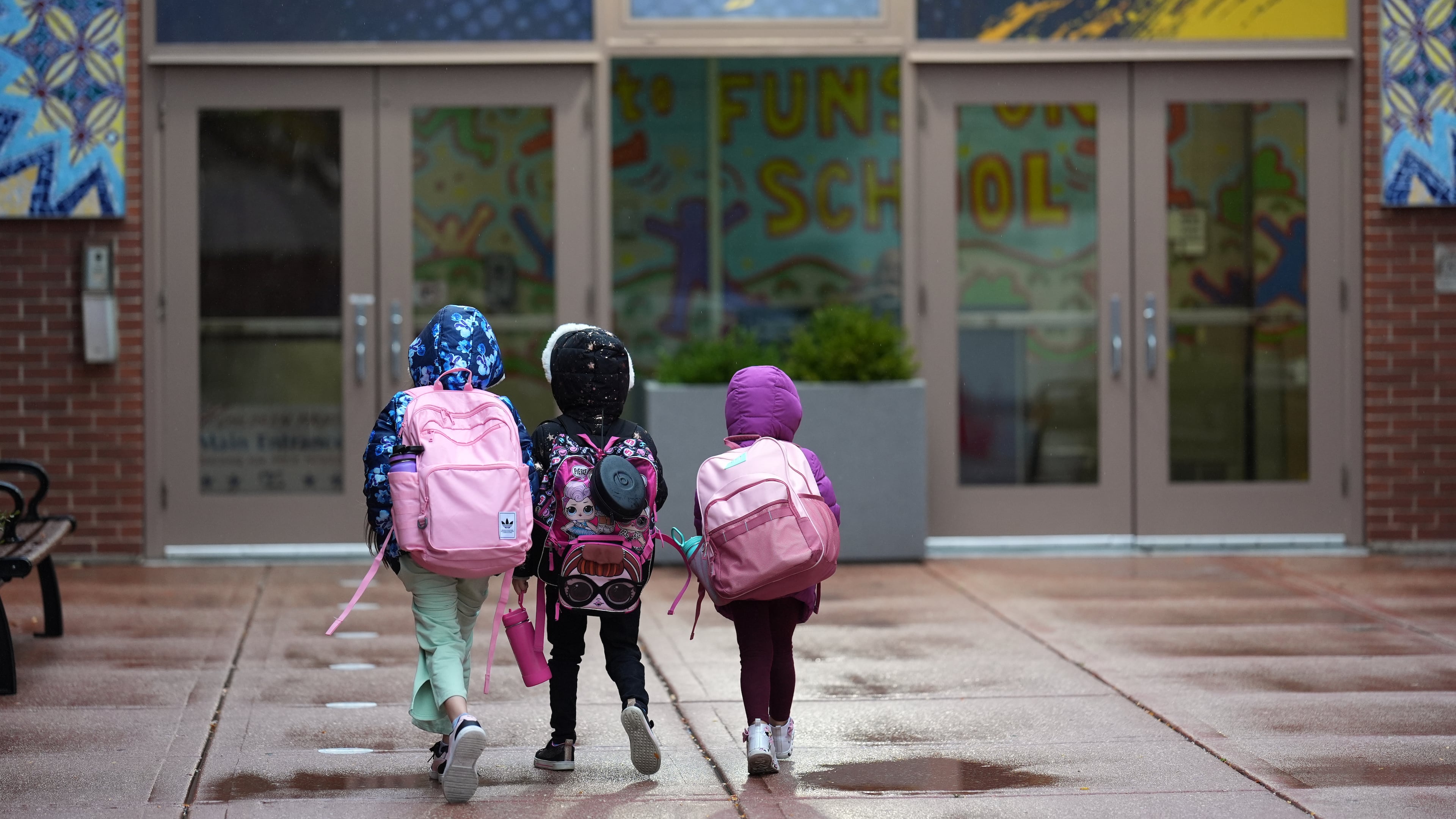Three sisters, whose single mother fears being mistakenly detained by federal immigration agents because she is of Puerto Rican descent and speaks Spanish, walk into Funston Elementary School after being dropped off for the start of the school day, in Chicago's Logan Square neighborhood, Wednesday, Oct. 15, 2025. (AP Photo/Rebecca Blackwell)