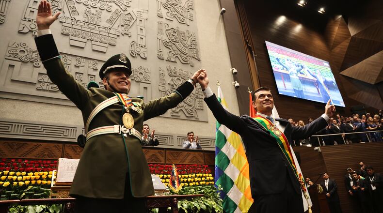President Rodrigo Paz, right, and Vice President Edman Lara hold hands after the swearing-in ceremony in La Paz, Bolivia, Saturday, Nov. 8, 2025. (Luis Gandarillas, Pool Photo via AP)