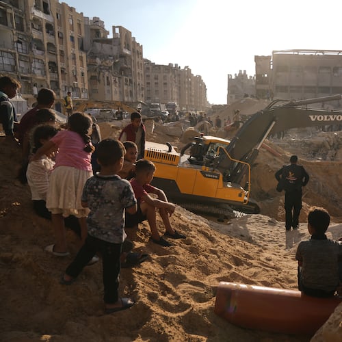 Palestinians watch machinery and some workers from Egypt searching for the bodies of hostages at Hamad City, in Khan Younis, southern Gaza Strip, Sunday, Oct. 26, 2025. (AP Photo/Jehad Alshrafi)