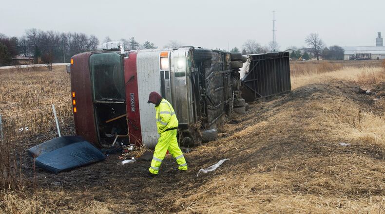 A tow truck operator walks around a bus that flipped over while carrying the Columbus Cottonmouths, a minor-league hockey team. (David Zalaznik/Journal Star via AP)