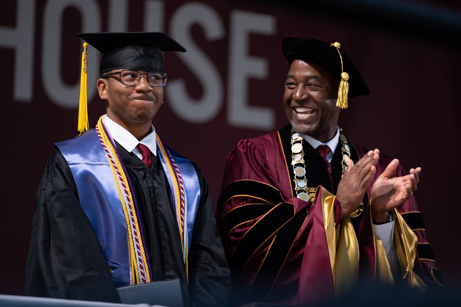 Morehouse College valedictorian Yamir Richmond (left) grins after President F. Dubois Bowman announced that it was Richmond’s birthday during the Morehouse College graduation Sunday, May 17, 2026. (Ben Gray for the AJC)