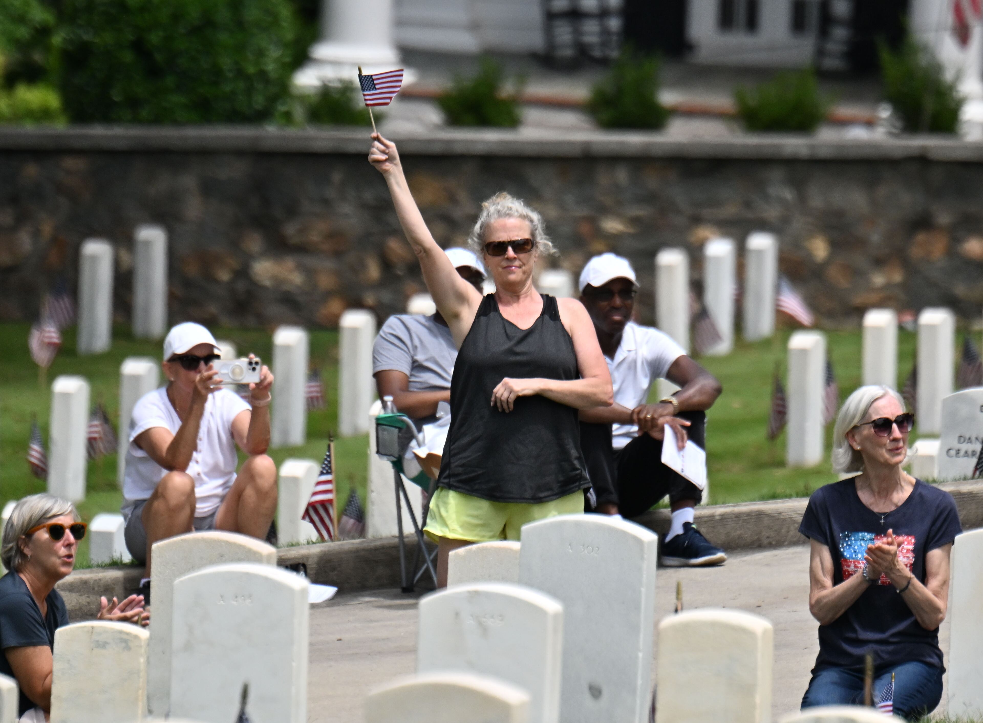 A spectator waves an American flag during the Memorial Day ceremony at Marietta National Cemetery, Monday, May 26, 2025, in Marietta. (Hyosub Shin / AJC)