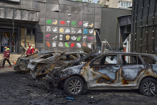 Municipal workers clean up near burnt cars in the residential area following Russia's drone attack in Kyiv, Ukraine, Sunday, May 4, 2025. (AP Photo/Efrem Lukatsky)