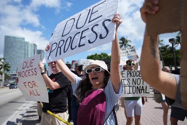 People hold signs and chant slogans during a protest against the Trump administration, Saturday, April 19, 2025, in Miami. (AP Photo/Lynne Sladky)