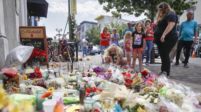 Mourners bring flowers to a makeshift memorial Tuesday, Aug. 6, 2019, for the slain and injured in the Oregon District after a mass shooting that occurred early Sunday morning in Dayton.