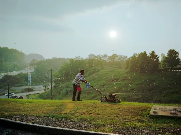 Paul Graham’s “Pittsburgh (detail)” captures the typically overlooked effort of a man mowing the grass on a steep hillside at a generic highway exit of cheap motels and gas stations. Graham’s “The Whiteness of the Whale” exhibit is at the High Museum of Art. COPYRIGHT PAUL GRAHAM / CONTRIBUTED BY PACE/MACGILL GALLERY, NEW YORK