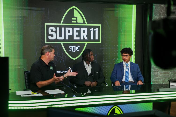 (L-R) DawgNation’s Brandon Adams interviews Creekside’s Gary Walker and Valdosta’s Marquis Fennell during the taping of the Super 11 reveal show at Score ATL in Roswell on Aug. 3, 2026. (Arvin Temkar/AJC)